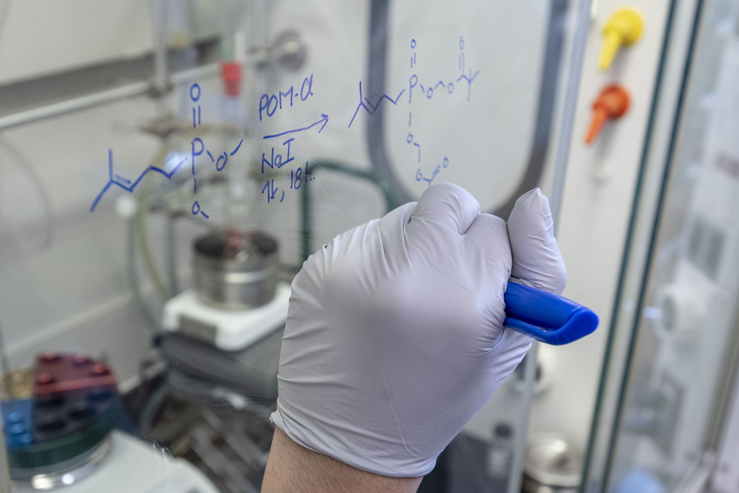 student writing equations on a clear whiteboard